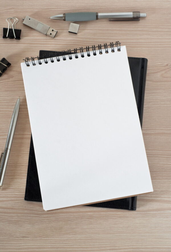 A blank white notepad with a pen lying beside it.