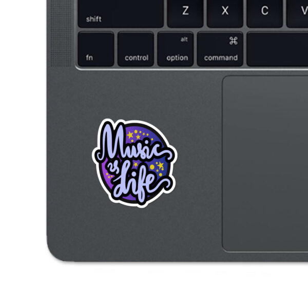 A sticker with the words "MUSIC IS LIFE" in blue and purple colors with a black outline, placed on a laptop.